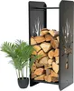 A black metal firewood rack filled with logs, next to a potted artificial plant. Podgląd zdjęcia produktu