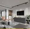 A modern living room with a grey sofa, armchair, coffee tables, and a media console with a TV. Voir les images du produit