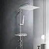 A modern shower system with a square overhead shower head and a handheld shower head, mounted on a chrome pole with a shelf, against a textured gray wall. Náhled obrázku produktu