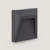 A dark gray, geometric outdoor LED wall light is shown mounted on a light gray wall. Produktbild-Vorschau