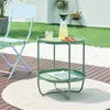 An outdoor patio scene with a green side table, a light blue chair, and a rug. Náhled obrázku produktu