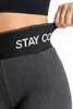 Close-up of the waistband of dark gray leggings with black trim and white text. Produktbild-Vorschau