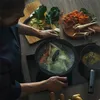 A person is cooking vegetables in a pot on a stovetop. Podgląd zdjęcia produktu