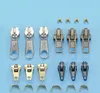 A collection of zipper sliders and pull tabs arranged on a light blue background. Podgląd zdjęcia produktu