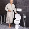An elderly man in a bathrobe stands next to an open toilet in a modern bathroom. Produktbild-Vorschau