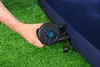 A hand is holding an electric pump to an inflatable mattress on grass. Produktbild-Vorschau