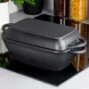 A black cast iron pot with a lid sits on a black glass stovetop. Produktbild-Vorschau