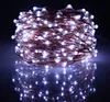 A coiled string of white LED lights with copper wire, reflected on a dark surface. Produktbild-Vorschau