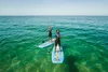 Two people stand on paddleboards in clear turquoise water under a bright blue sky. Produktbild-Vorschau