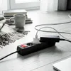 A power strip with two adapters plugged in, placed on a wooden floor next to a stack of books and a blanket. Podgląd zdjęcia produktu