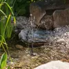A small solar-powered fountain is operating in a garden pond with rocks and plants. Produktbild-Vorschau