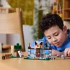 A young boy is playing with a LEGO Minecraft set on a wooden table. Produktbild-Vorschau