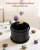Rocks are falling into a black tumbling machine on a white table. Produktbild-Vorschau