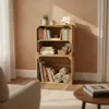 A wooden crate bookshelf filled with books and rolled blankets, placed in a room with a textured wall and wooden floor. Náhled obrázku produktu