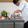 A chef in a kitchen using a VERTES tomato slicer. Voir les images du produit