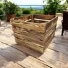 A wooden crate sits on a wooden deck with a blurred background of greenery and a railing. Anteprima dell’immagine prodotto
