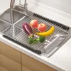 A roll-up dish drying rack filled with fruits and vegetables placed over a stainless steel kitchen sink. Náhled obrázku produktu