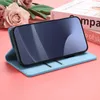 A light blue phone case with a phone inside is displayed on a pink surface with flowers in the background. Produktbild-Vorschau