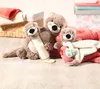Three plush otter toys are arranged on a wooden floor, with blankets and a basket in the background. Náhľad obrázku produktu