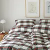 A bed with plaid bedding and pillows. Produktbild-Vorschau
