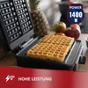 A waffle maker with waffles inside, with fruits and a pineapple in the background. Produktbild-Vorschau