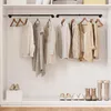 A clean, organized closet interior with clothing hanging on two parallel black metal rods mounted on the wall. Shoes are neatly arranged on the floor and a small white shelf. Produktbild-Vorschau