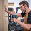 A man is using a Bosch cordless impact wrench to screw a long screw into a wooden panel. He is wearing safety glasses and earplugs. Voir les images du produit
