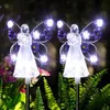 Two angel-shaped solar garden lights with purple butterfly wings are illuminated in a garden at night. Náhľad obrázku produktu