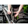 A person is attaching a black accessory to the seat post of a gray electric bicycle. Voir les images du produit