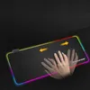 A hand is shown moving a mouse on a large RGB gaming mousepad with colorful LED lighting around the edges. Yellow arrows indicate movement. Produktbild-Vorschau