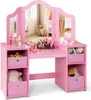 A pink children's vanity table with a tri-fold mirror and various accessories, including toy makeup and stuffed animals.