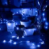 A collection of potted plants decorated with blue LED string lights at night. Produktbild-Vorschau