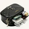 A black quilted leather handbag with a cat charm, partially open to reveal its contents. Náhľad obrázku produktu