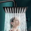 A woman is enjoying a shower under a modern square shower head. Produktbild-Vorschau