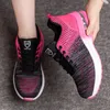 A pair of pink and black athletic shoes are shown, with one shoe on a person's foot and the other being held by a hand. Produktbild-Vorschau