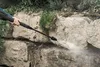 A person is using a pressure washer to clean a stone wall. Produktbild-Vorschau