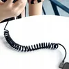 A person's hands are holding a phone, with a coiled black cable extending from it onto a white table. Anteprima dell’immagine prodotto