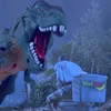 A toy dinosaur is roaring at a person sitting on a toilet. Produktbild-Vorschau