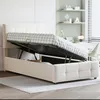 A beige upholstered bed frame with the mattress lifted to reveal the storage compartment underneath. Produktbild-Vorschau