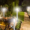 A garden at night, illuminated by several modern outdoor lamps. Produktbild-Vorschau
