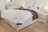 A neatly made bed with a white duvet and purple throw blanket. Produktbild-Vorschau