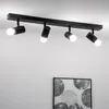 A black ceiling light fixture with four adjustable spotlights is mounted on a white ceiling. Voir les images du produit