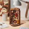 A miniature bookshelf diorama with a desk, chair, and lamp, set on a wooden desk. Náhled obrázku produktu