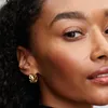 Close-up of a woman's face wearing gold earrings. Produktbild-Vorschau