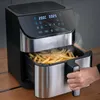 A hand is pulling out the basket of an air fryer filled with french fries, with steam rising from the basket. Produktbild-Vorschau
