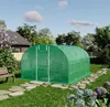 A green greenhouse in a backyard setting with a stone path leading to it. Produktbild-Vorschau