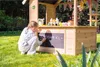 A young girl is playing at a wooden ice cream stand in a garden. Produktbild-Vorschau