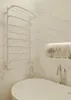 A modern bathroom with a white bathtub, a white towel warmer, and a built-in shelf with toiletries. Náhľad obrázku produktu