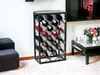 A modern black metal wine rack filled with wine bottles, placed in a living room setting next to a dark upholstered chair and a coffee table. Produktbild-Vorschau