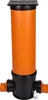 A vertical sewage inspection chamber with a black lid, an orange pipe, and a black base with two side connections. A small bottle of lubricant is placed at the bottom right. Produktbild-Vorschau